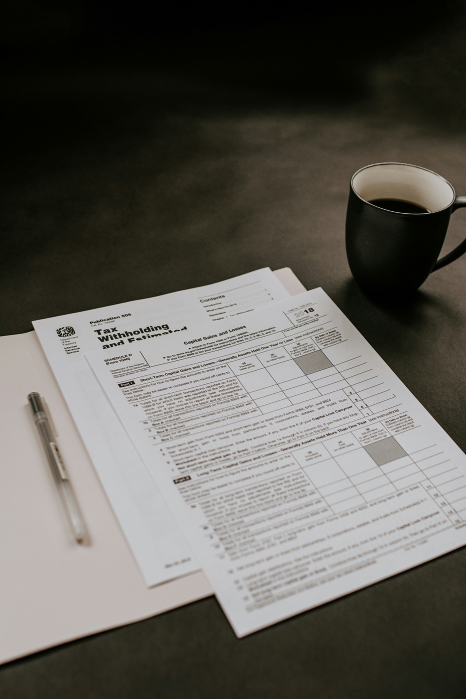 Tax forms, a pen and a cup of coffee on a desk